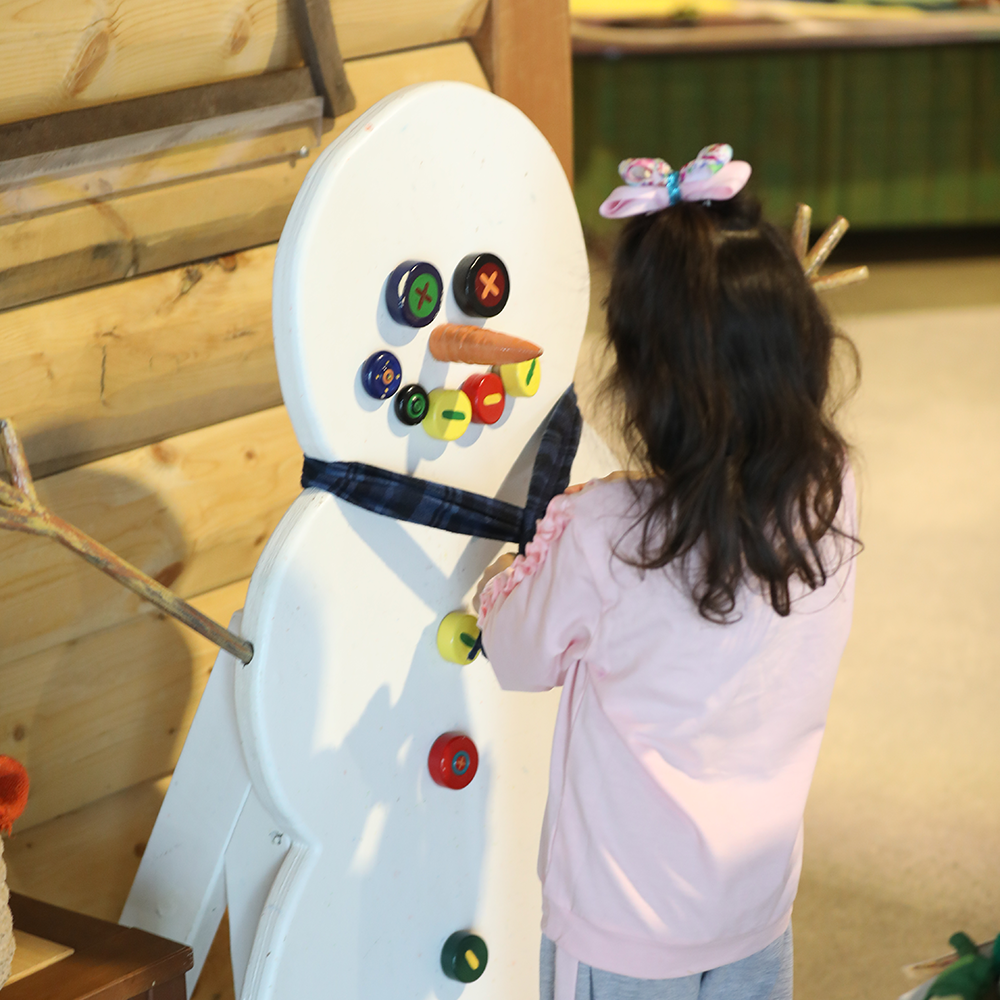 Girl Dressing Snowman in A Northwoods Winter exhibit at the Children's Museum
